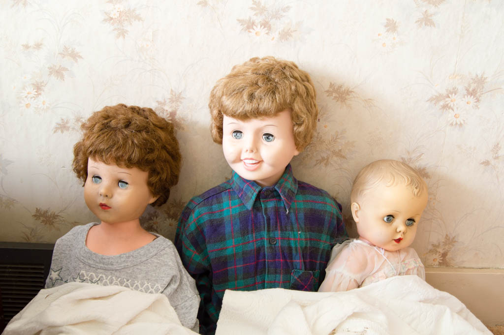 Three dolls inside the abandoned house of toys
