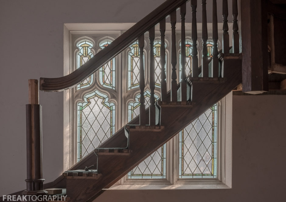close crop urban exploration photo of a stained glass window and stairs in an abandoned ontario church