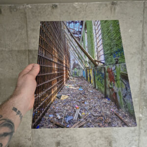 Rusted jail bars lining a debris-covered corridor with graffiti-covered walls inside the abandoned Essex County Jail in New Jersey.