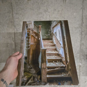 Debris-covered wooden staircase with peeling green walls and torn curtains inside an abandoned house in Southwestern Ontario.