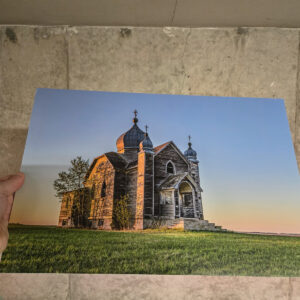 An abandoned wooden Ukrainian church with onion domes and crosses standing in an open prairie field at sunrise in Saskatchewan.