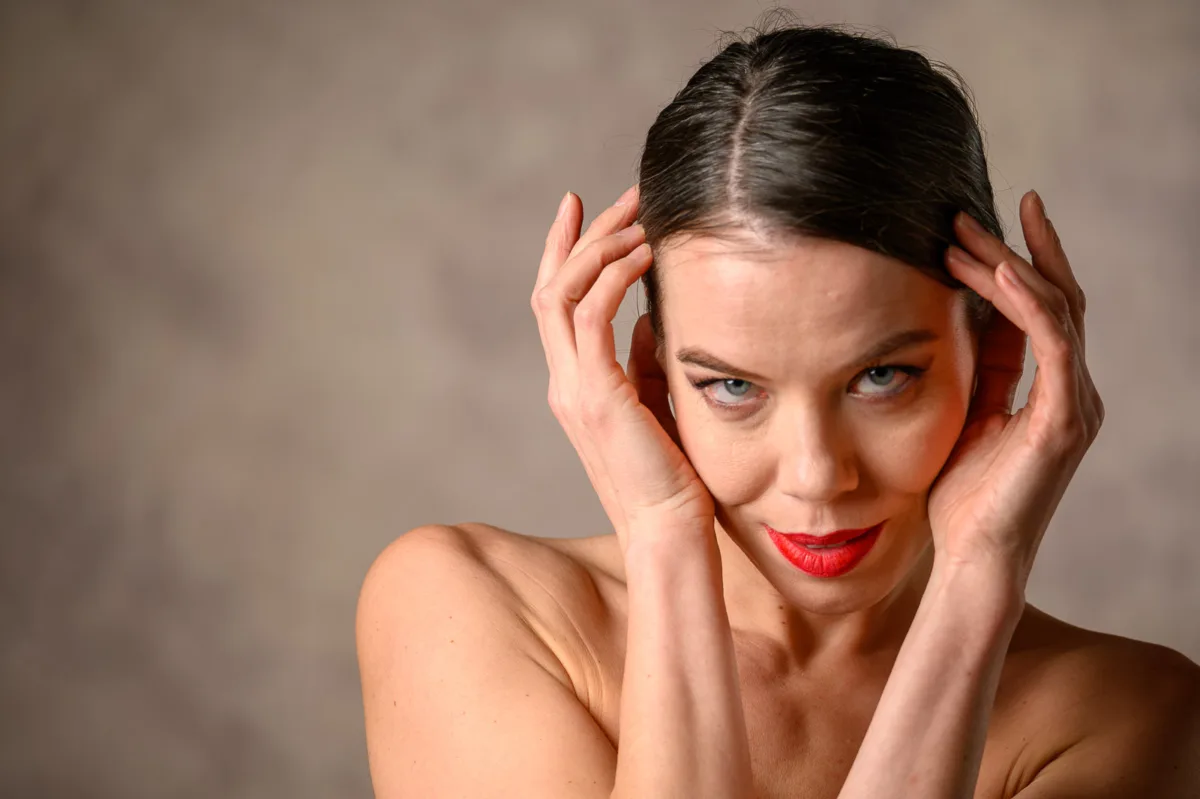 Playful beauty portrait of woman with hands near head smiling