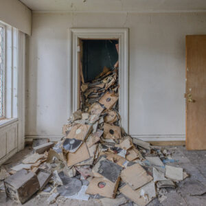 A pile of decayed vinyl records spilling out of a doorway inside the attic of an abandoned funeral home and music school in Detroit.