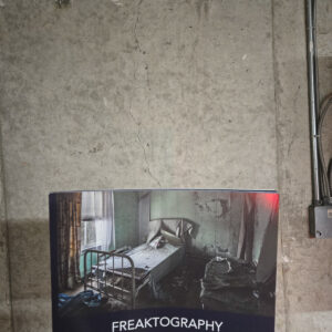 Softcover Freaktography Uninhabited coffee table book with a cover photo of an abandoned bedroom with a rusted bed frame and peeling wallpaper.